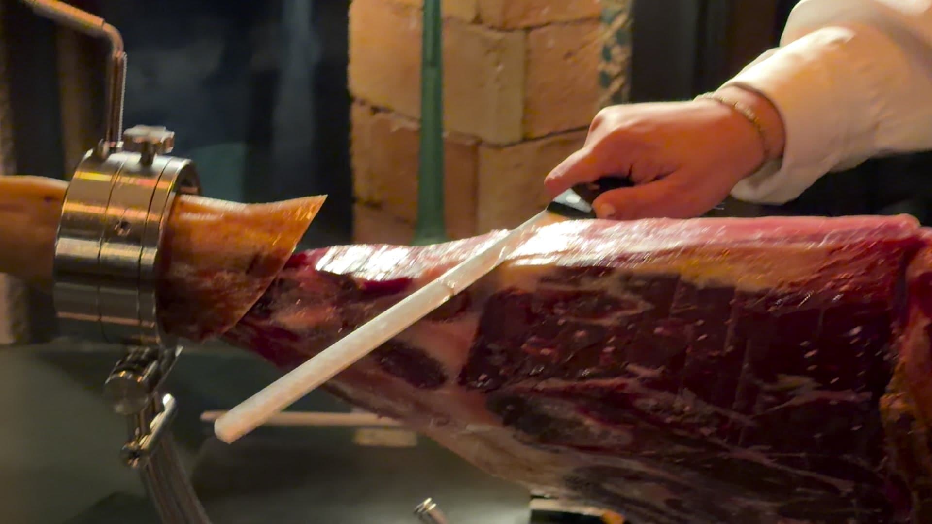 Corte a cuchillo de un jamón de bellota en el jamonero durante un evento