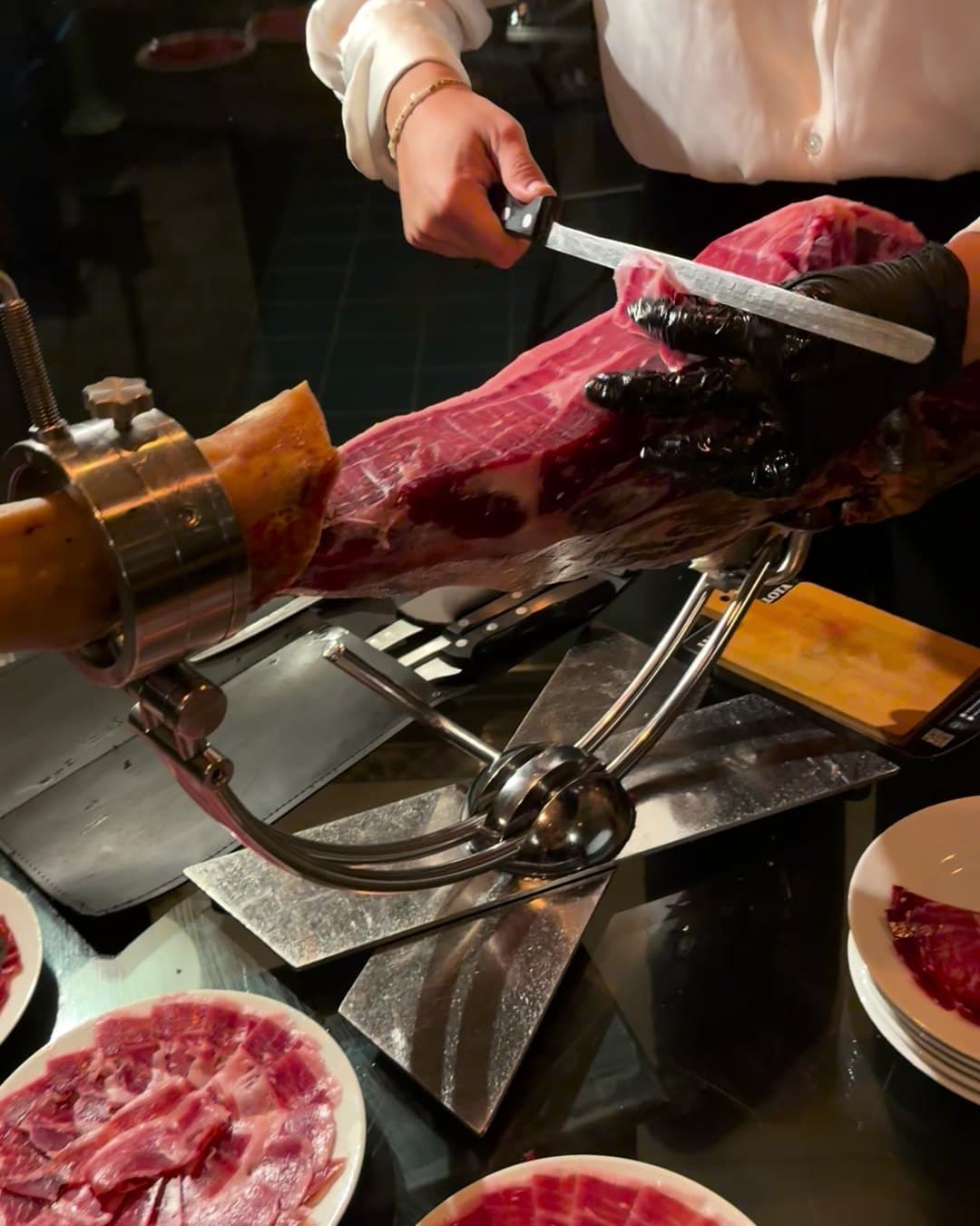 Una cortadora sirve jamón recién cortado junto a los platos emplatados